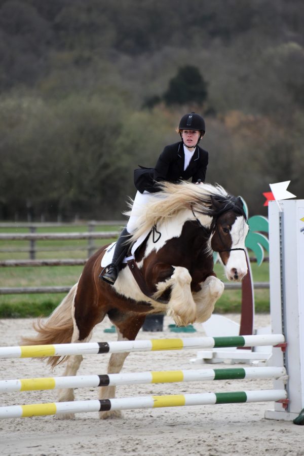 Photo de Coline Gosset sautant un obstacle sur un cheval blanc et marron